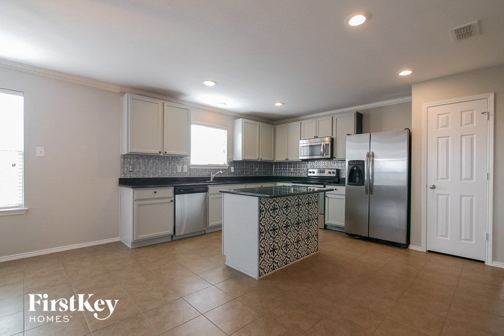 a kitchen with an island and stainless steel appliances and white cabinets