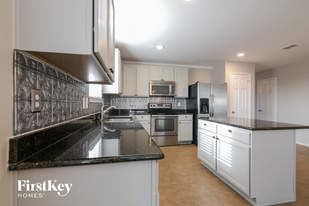 a kitchen with black counter tops and white cabinets and appliances