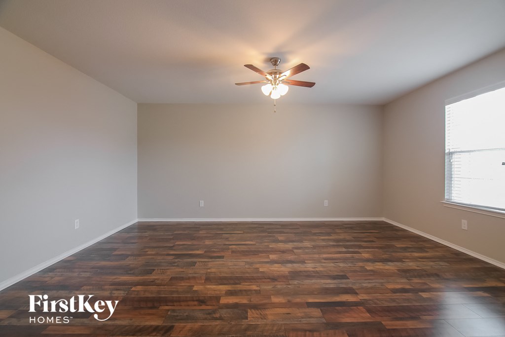 an empty living room with a ceiling fan and wood floors
