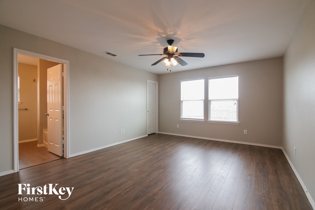 an empty living room with wood floors and a ceiling fan