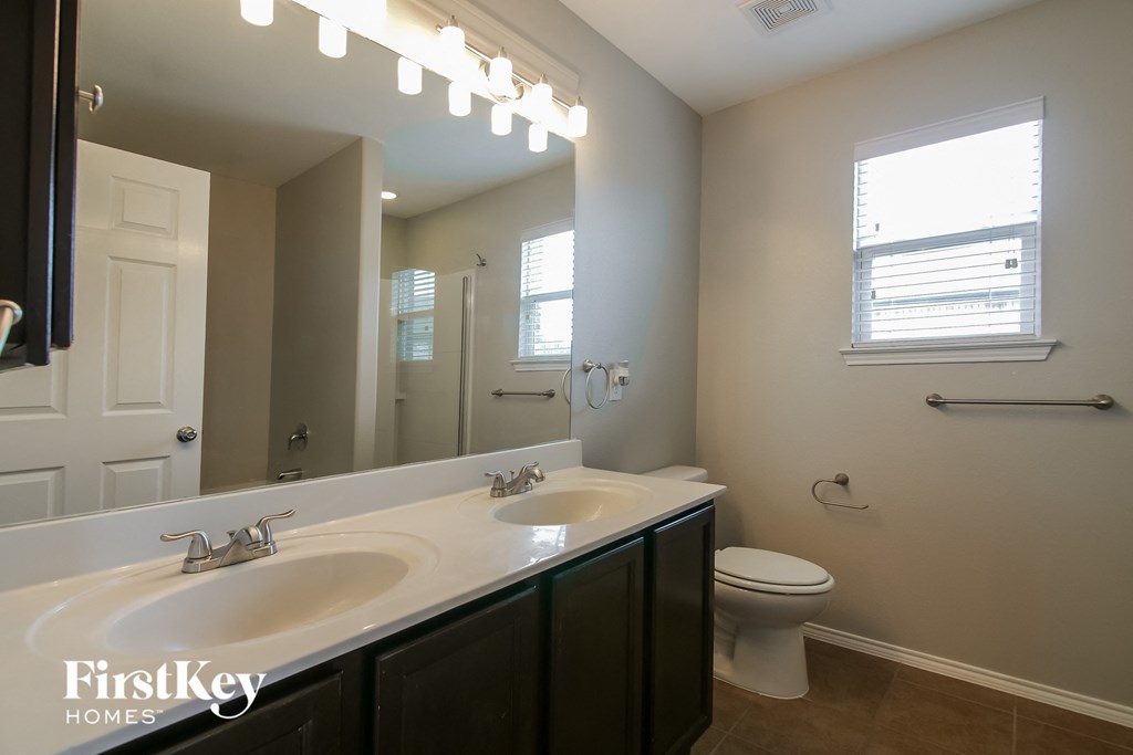 a bathroom with two sinks and a toilet and a large mirror