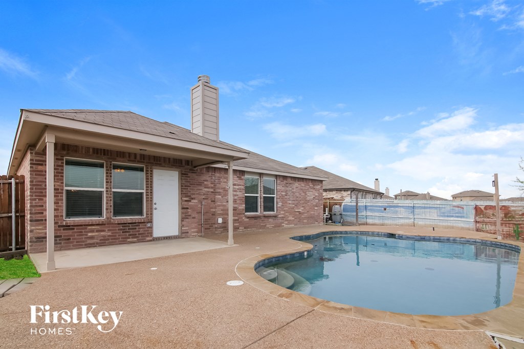 a pool is outside of a brick house with a pool