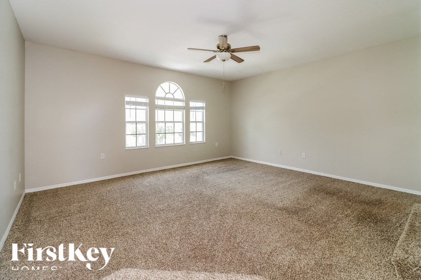 a living room with carpet and a ceiling fan