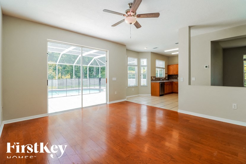 an empty living room with wood floors and a sliding glass door to a pool