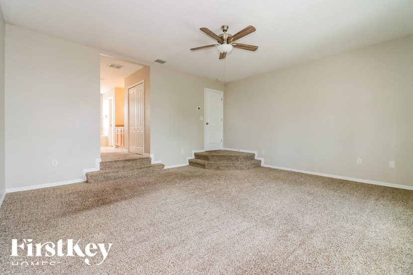 an empty living room with carpet and a ceiling fan