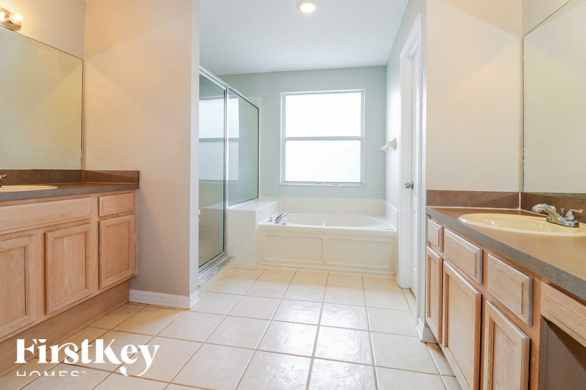 a bathroom with two sinks and a tub and a shower