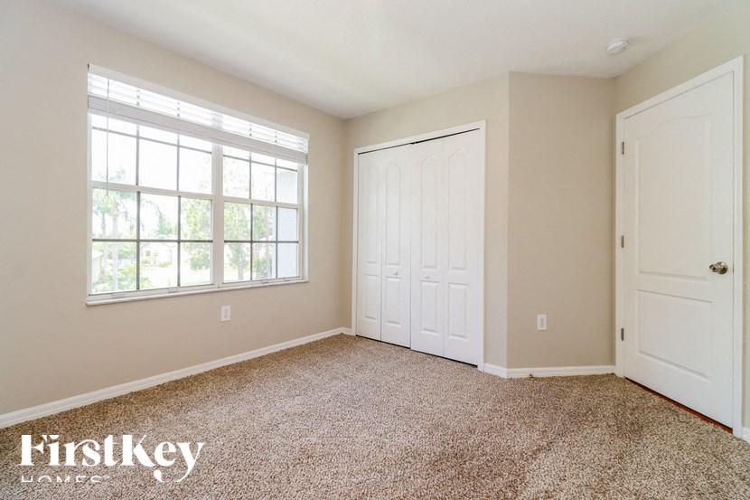 a bedroom with carpet and two doors and a window