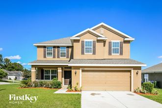 a beige house with a garage and a lawn