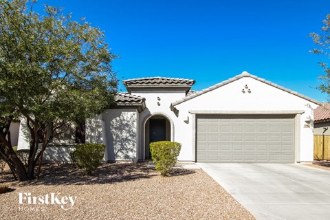 a white house with a garage and a tree