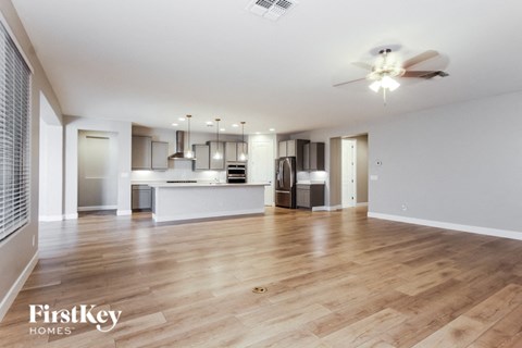 an open living room with a kitchen and a ceiling fan