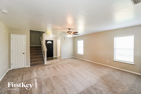 A spacious room with a carpeted floor and a ceiling fan.