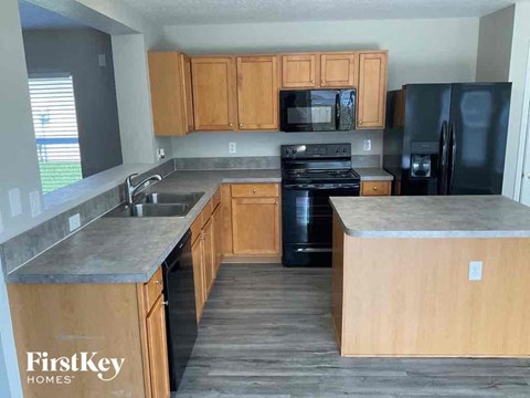 A kitchen with wooden cabinets and a black fridge.