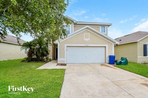a beige house with a white garage door and a lawn