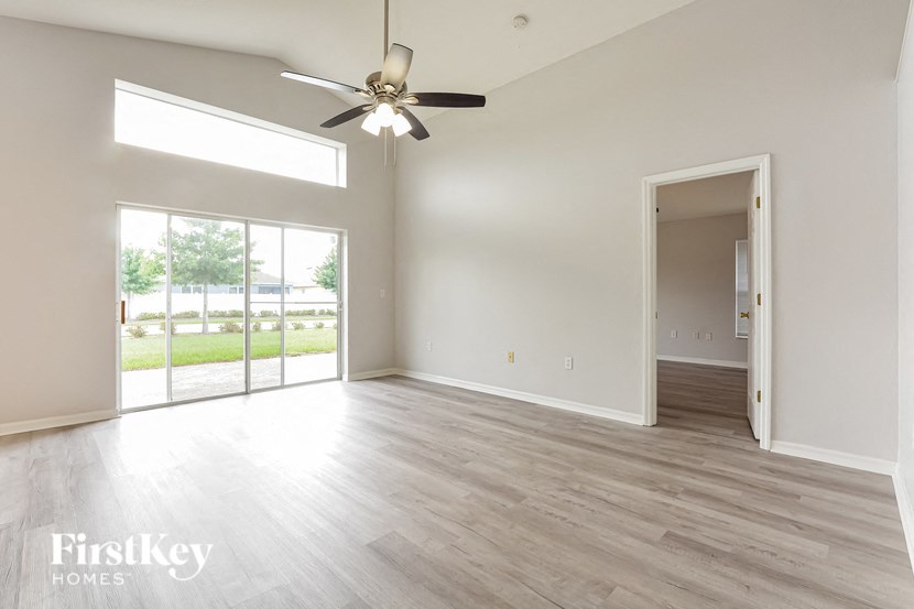 an empty living room with white walls and a ceiling fan