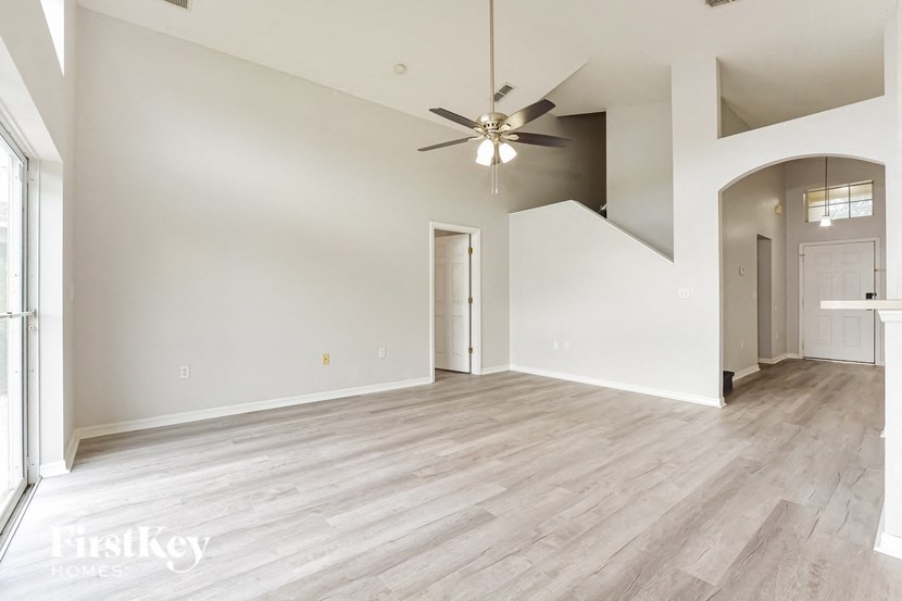an empty living room with a ceiling fan and white walls