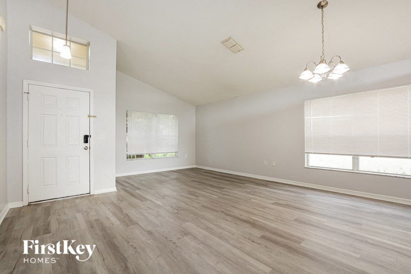an empty living room with a white door and a window