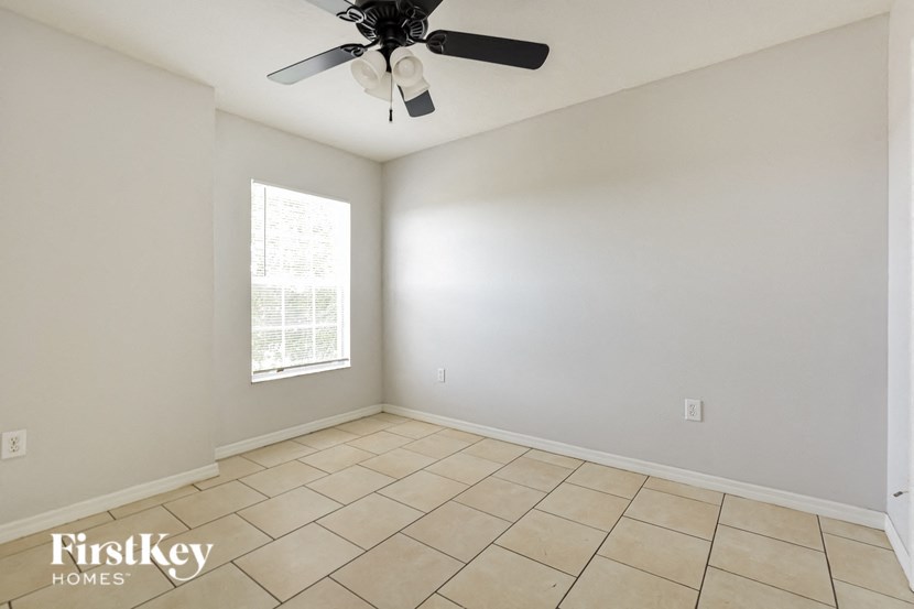 an empty room with a ceiling fan and a window