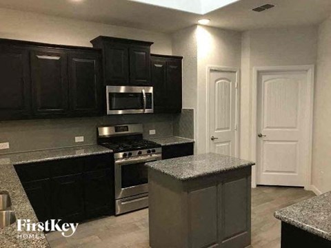 a kitchen with black cabinets and stainless steel appliances