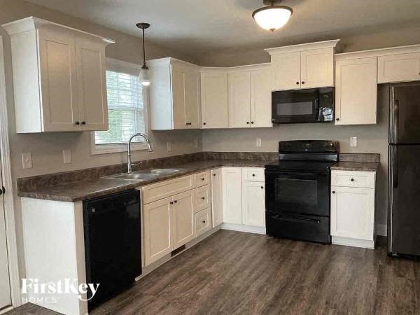 A kitchen with black appliances and white cabinets.