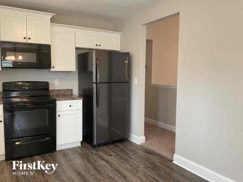 A black refrigerator in a kitchen with white cabinets.