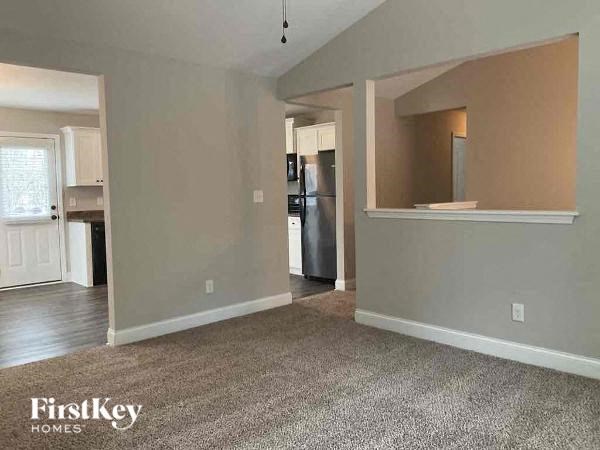 A spacious room with a refrigerator in the middle and a window on the left.