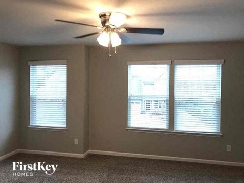 a bedroom with a ceiling fan and three windows