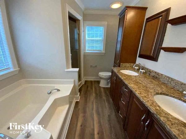 A well-lit, spacious bathroom with a bathtub, toilet, and sink.
