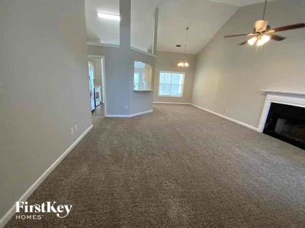 A spacious living room with a fireplace and a ceiling fan.