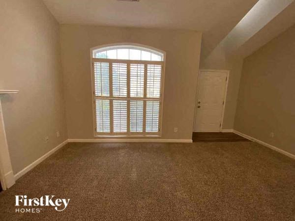 A room with a carpeted floor and a large window with blinds.