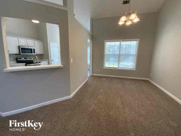 A room with a carpeted floor and a window with blinds.