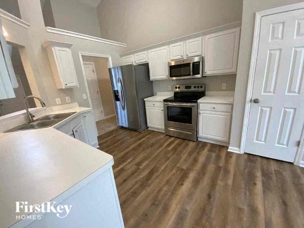 A kitchen with wooden floors and white cabinets.