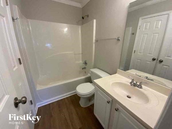 A white bathroom with a toilet, sink, and shower.