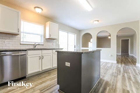 A kitchen with a stainless steel refrigerator and wooden floors.