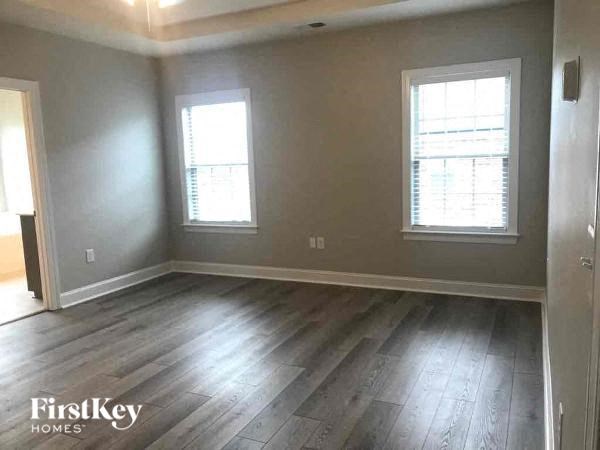 an empty living room with wood floors and two windows