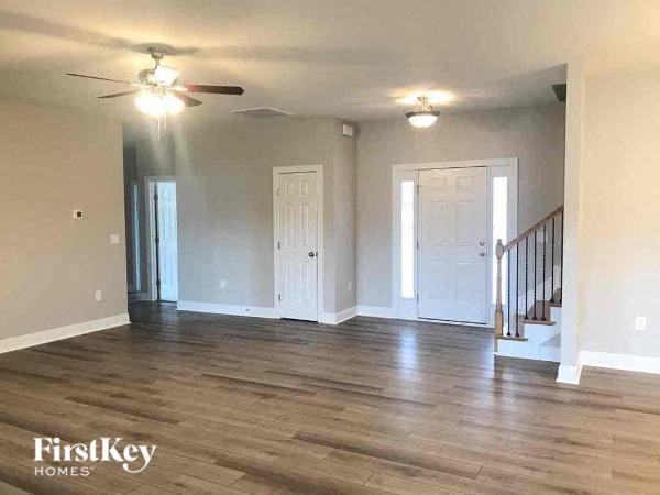 an empty living room with a ceiling fan and a staircase