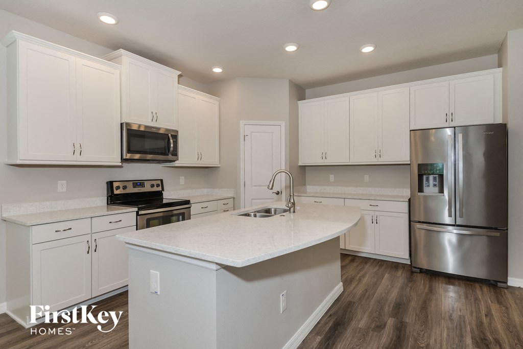 a white kitchen with stainless steel appliances and white counter tops