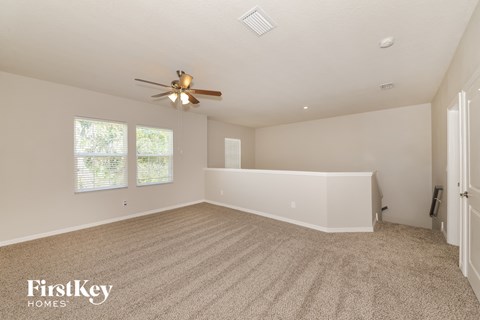a spacious living room with carpet and a ceiling fan