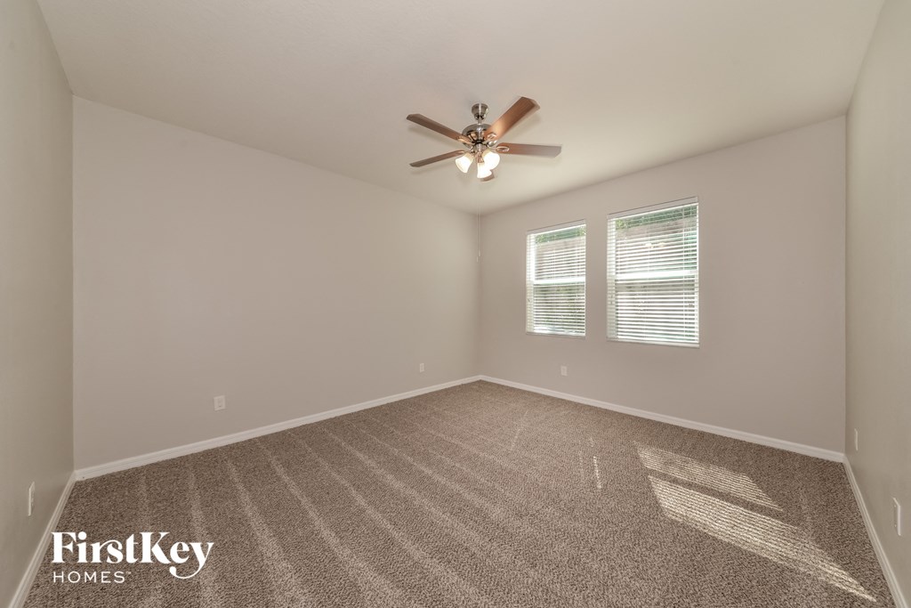 the spacious living room with ceiling fan and carpet