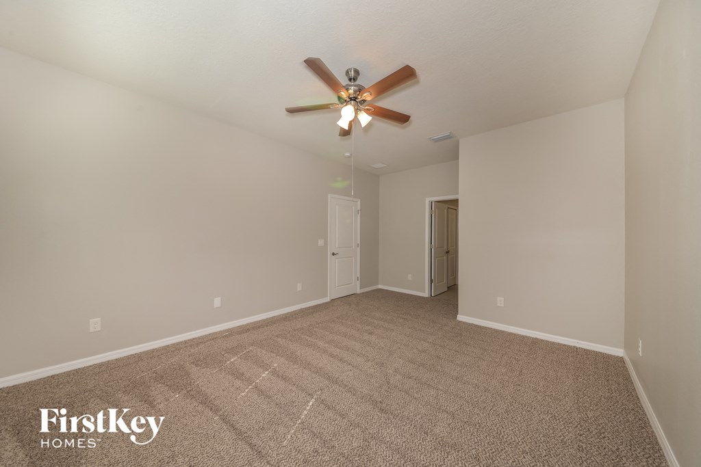 a spacious living room with carpet and a ceiling fan