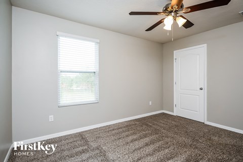 the spacious living room with ceiling fan and carpet