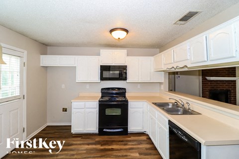 A kitchen with white cabinets and a black oven.