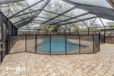 a patio with a pool in a screened in pool house