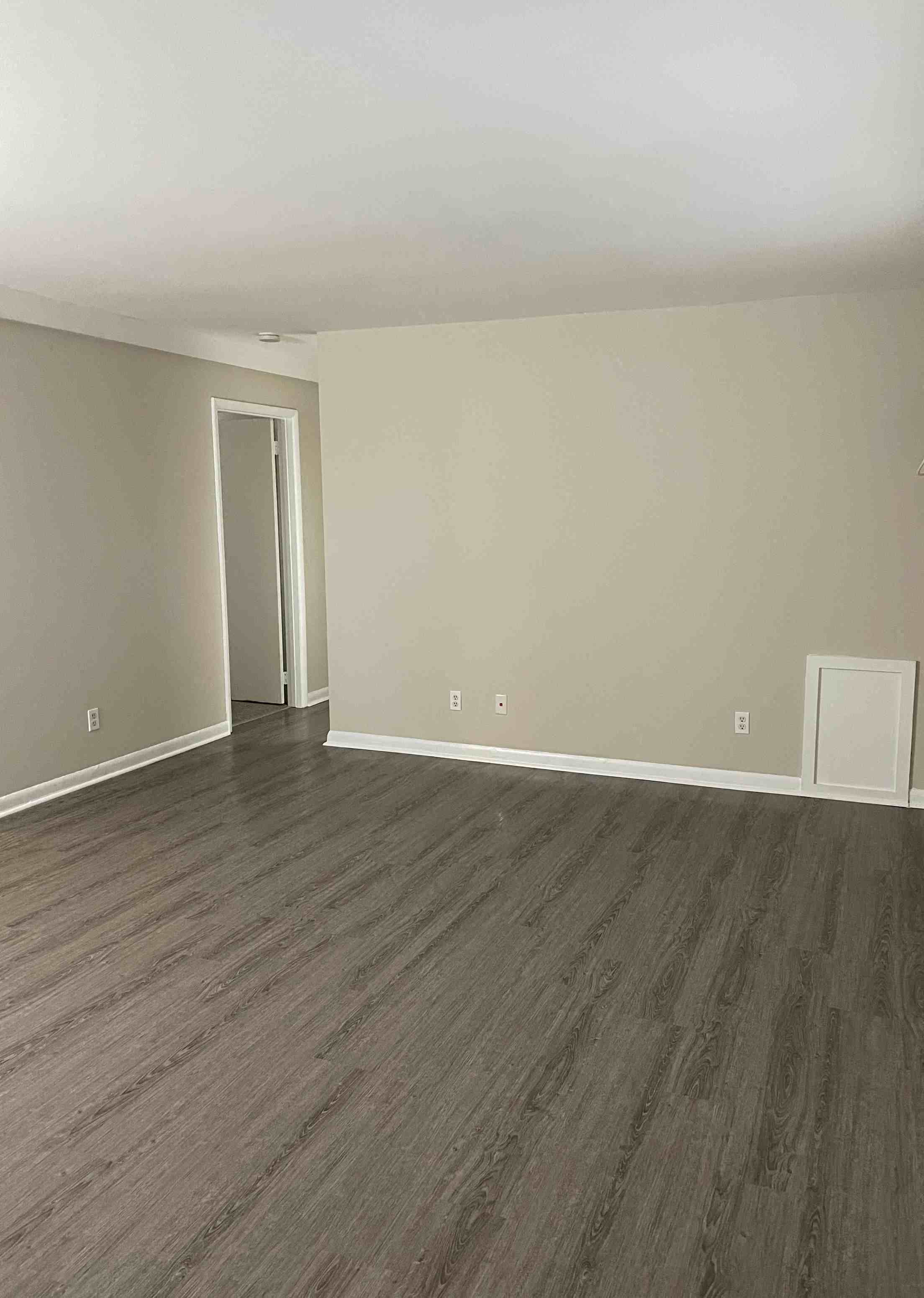 an empty living room with wooden floors and white walls
