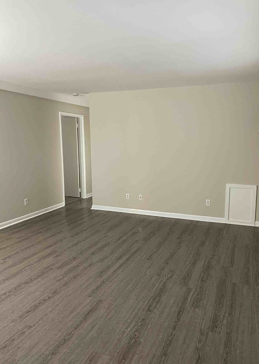 an empty living room with wooden floors and white walls