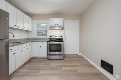 A kitchen with white cabinets and a stainless steel refrigerator.