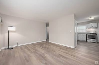 A spacious room with a kitchen area in the background.