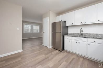 A kitchen with white cabinets and a stainless steel refrigerator.