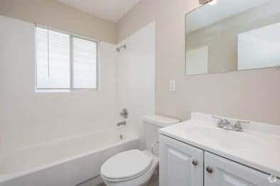A white toilet sits next to a bathtub in a bathroom.