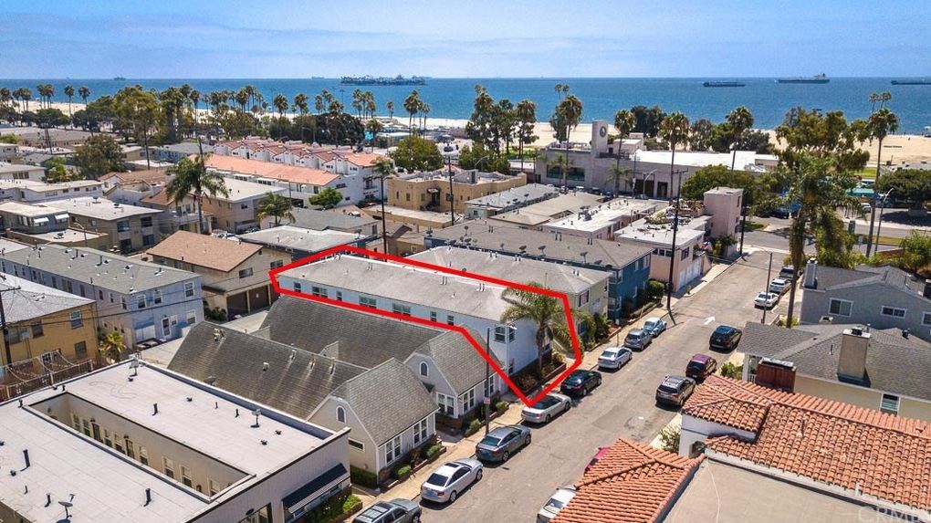 an aerial view of a building with a red roof and the ocean in the background