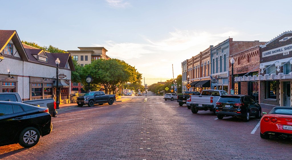 a sunset view of a city street with cars and buildings